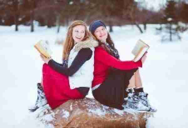 Two women sitting on a rock in the snow holding their Bibles